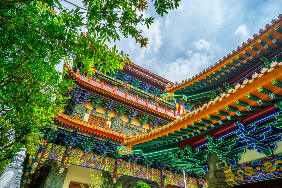 An ornate temple roof with gold tiles and painted green and blue eaves in Hong Kong